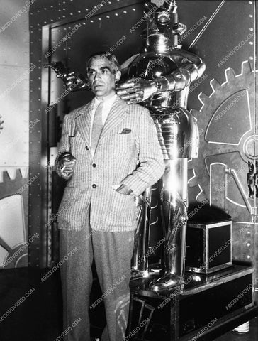 Boris Karloff posing w a shiney metal robot holding a gun 1593-17