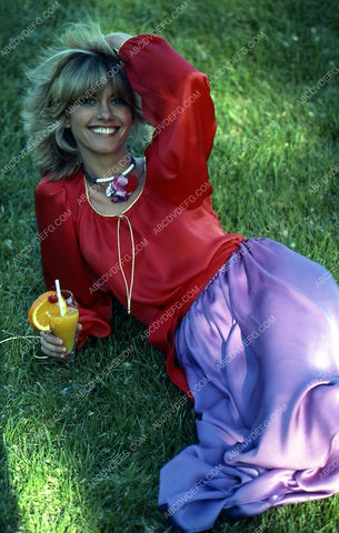 Olivia Newton-John enjoys fruity drink laying in the grass 35m-5402