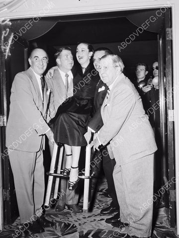Dorothy Lamour sitting on her stool and being hauled by friends 8b20-12202