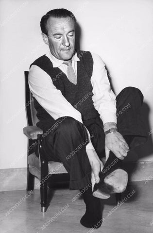 George Sanders in tiny chair takes of shoes for sore feet 8b20-14460