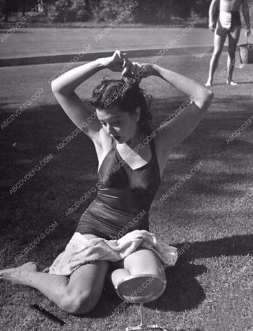 Ann Rutherford combing her hair on the lawn w sprinklers on 8b20-2403