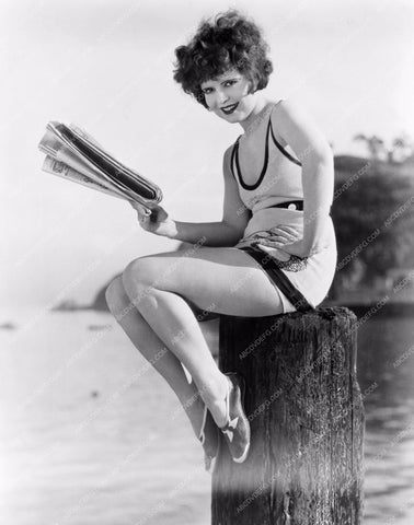Clara Bow in swimwear reads the newspaper on pier 8b20-7641