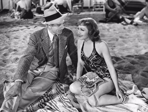 Gary Cooper Claudette Colbert sitting in the sand 8b20-7720