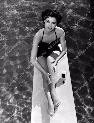 Cyd Charise sitting on the diving board applies some leg cream 8b20-9440